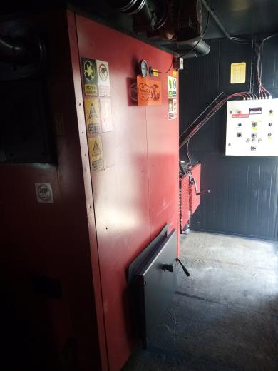 Wnętrze mobilnej kotłowni kontenerowej MAC 170 o mocy 170 kW na pellet i zrębkę marki Plomex-Pol z widocznym czerwonym kotłem i szafą sterowniczą.