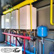 Wnętrze gazowej kotłowni kontenerowej o mocy 480 kW z kaskadą czterech kotłów ACV NexTra 120, żółtą instalacją gazową oraz rozdzielaczami hydraulicznymi.