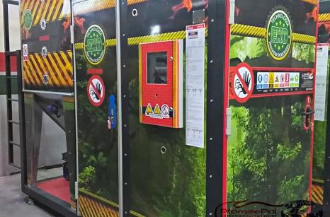 Kompaktowa kotłownia przemysłowa 100 kW w kontenerze, widok zewnętrzny z tablicami ostrzegawczymi i sterownikiem na elewacji, realizacja Plomex-Pol