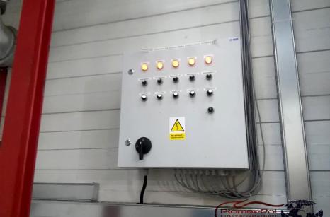 Szeroki widok instalacji rur doprowadzających ciepłe powietrze do maszyn wewnątrz hali produkcyjnej.